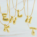 Gold plated balloon letter initial necklace with a stainless steel chain on a plain background