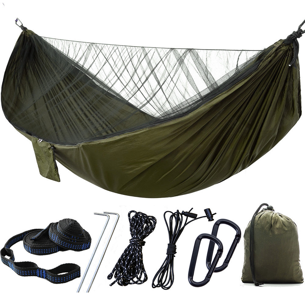 Portable camping hammock with openable mosquito net hanging between two trees outdoors