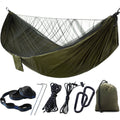 Portable camping hammock with openable mosquito net hanging between two trees outdoors