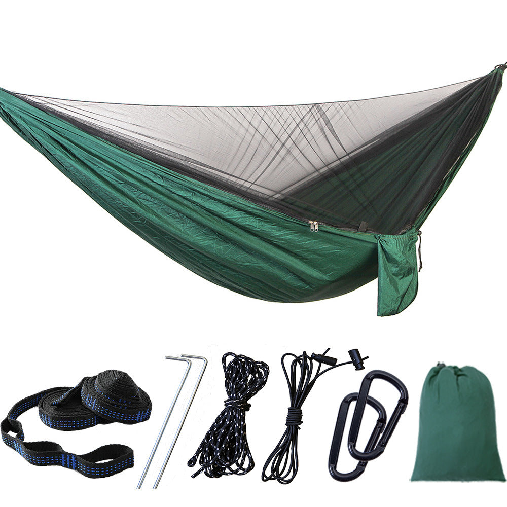 Portable camping hammock with openable mosquito net hanging between two trees outdoors — view 2