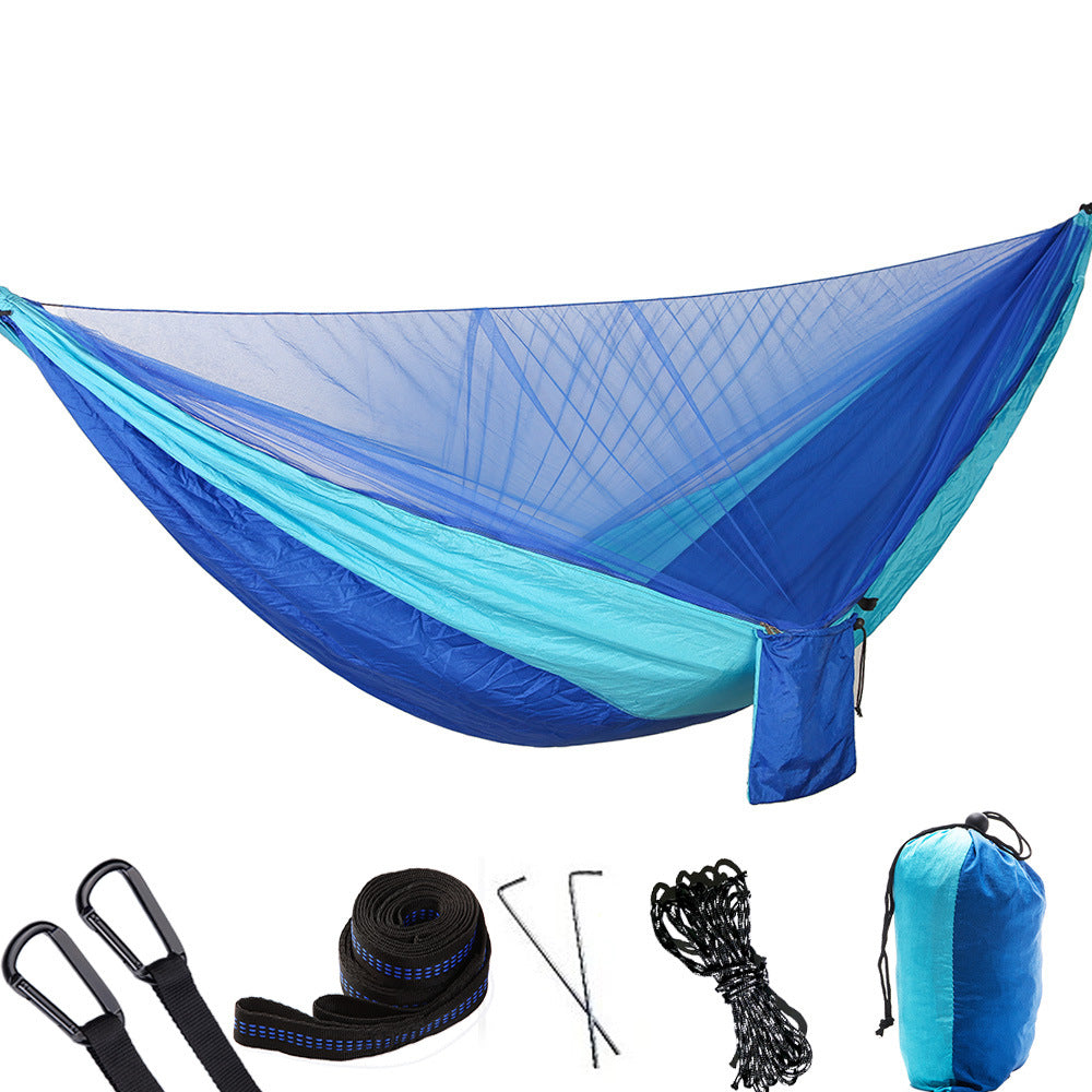 Portable camping hammock with openable mosquito net hanging between two trees outdoors — view 4