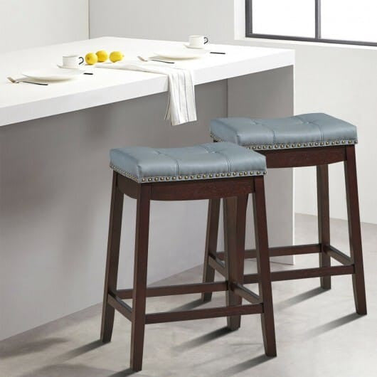 Set of two white backless counter stools featuring wooden legs nailhead trim and saddle seat