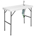 Folding camping cleaning table with integrated sink, extending sprayer, and durable white plastic workspace surface.