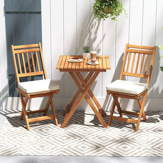 Acacia wood outdoor bistro set with folding table slatted chairs and soft white seat cushions