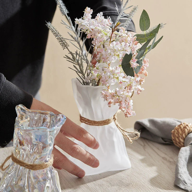Wrinkled glass vase with natural twine accent and folded paper texture on a modern table — view 2