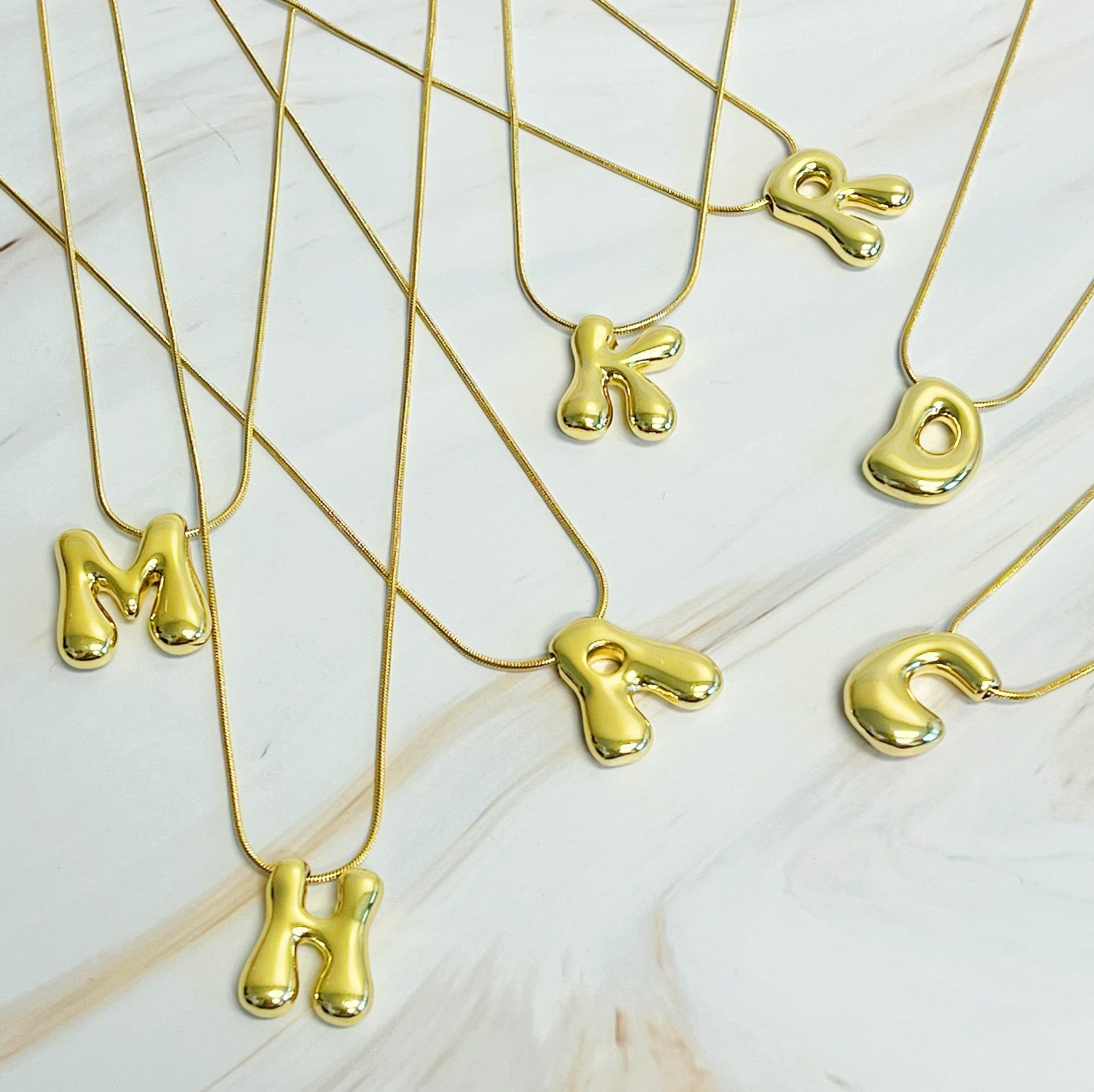 Gold plated balloon letter initial necklace with a stainless steel chain on a plain background — view 2