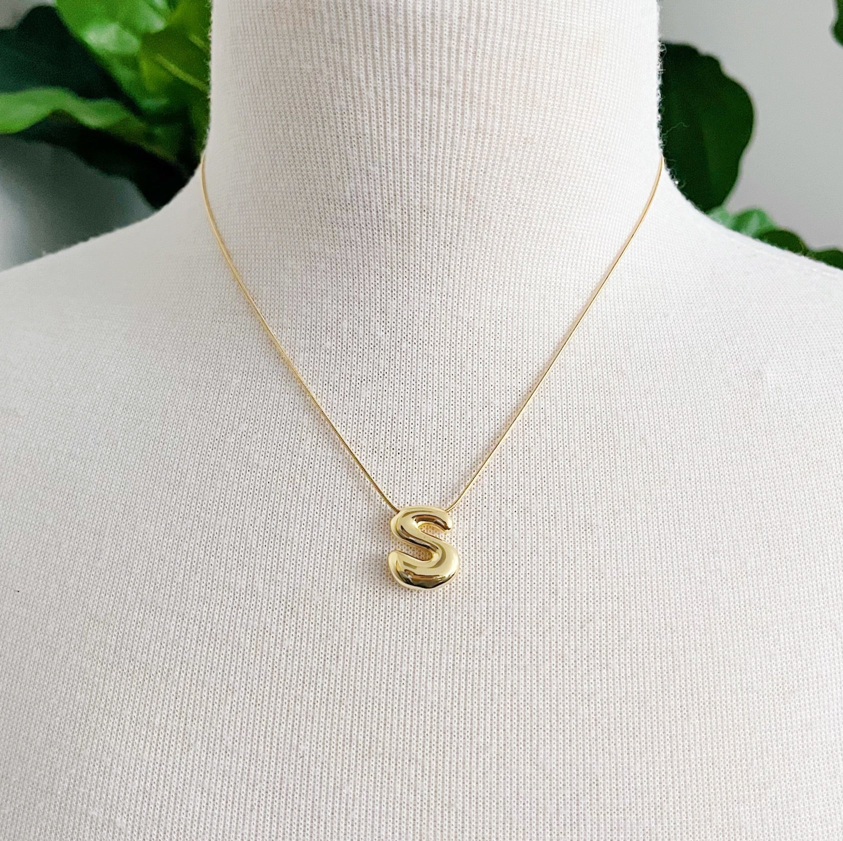 Gold plated balloon letter initial necklace with a stainless steel chain on a plain background — view 4