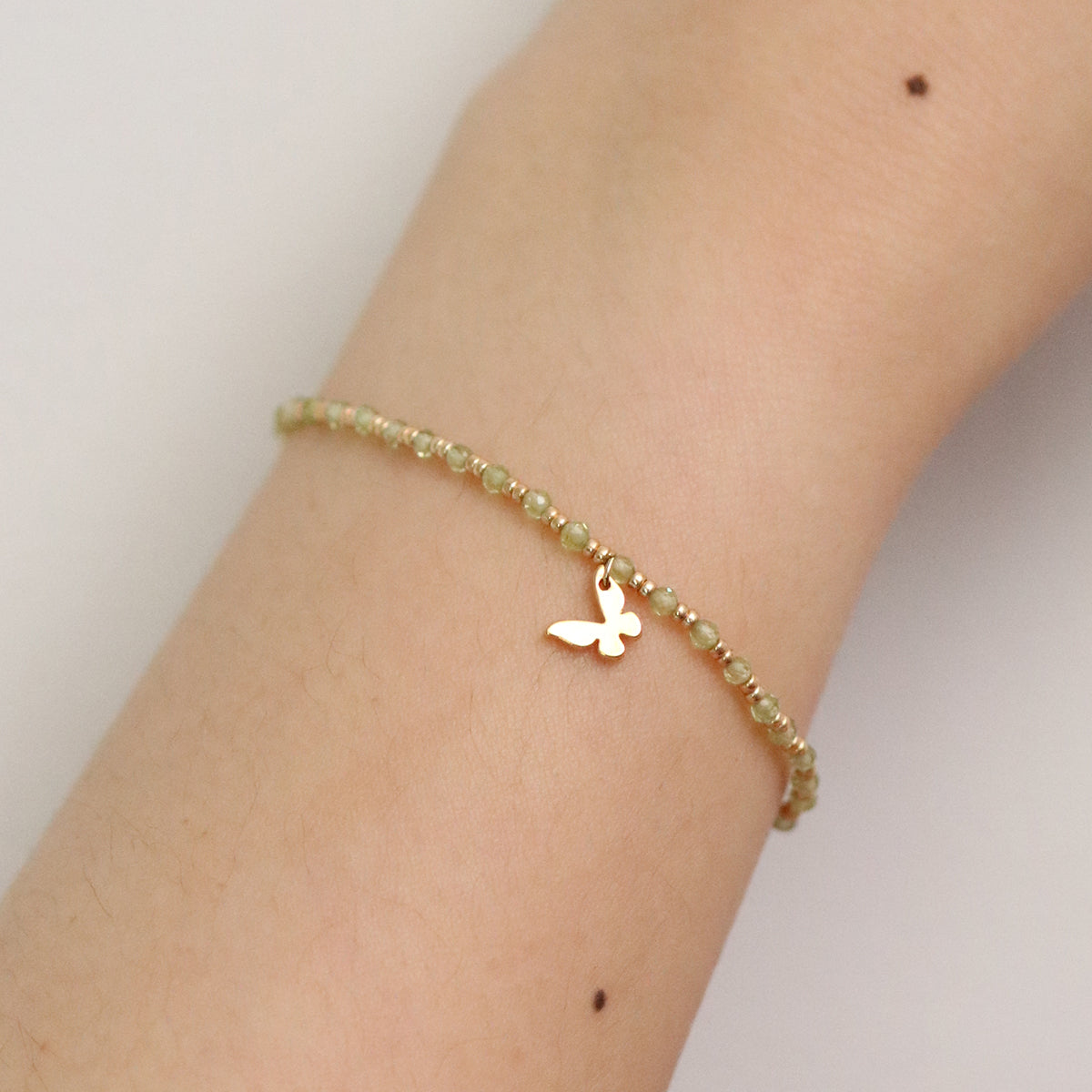 Gemstone butterfly charm stretch bracelet with delicate beads and a miniature metallic butterfly pendant