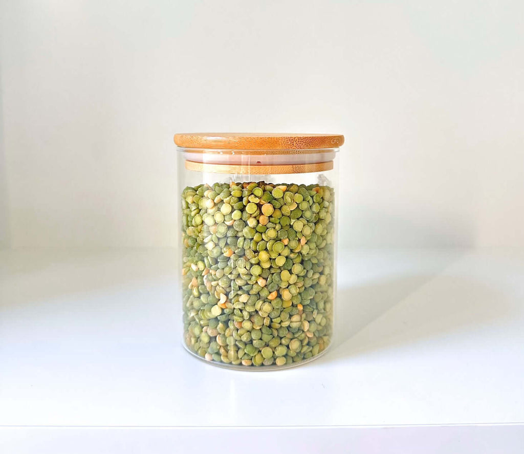 1050ml round clear glass storage jar with a natural airtight bamboo lid filled with dry ingredients