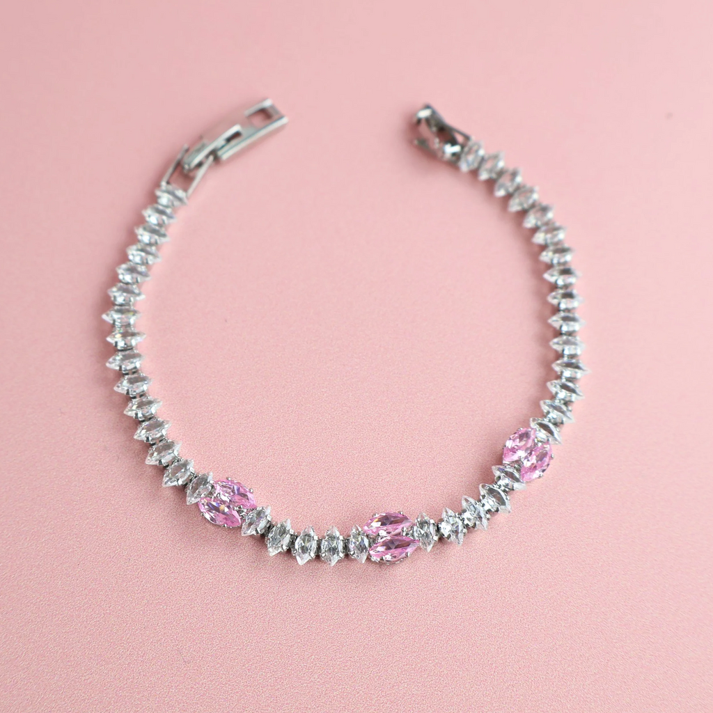 Silver bracelet with pink and clear zirconia stones on pink background