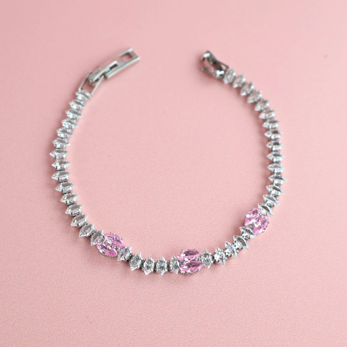 Silver bracelet with pink and clear zirconia stones on pink background