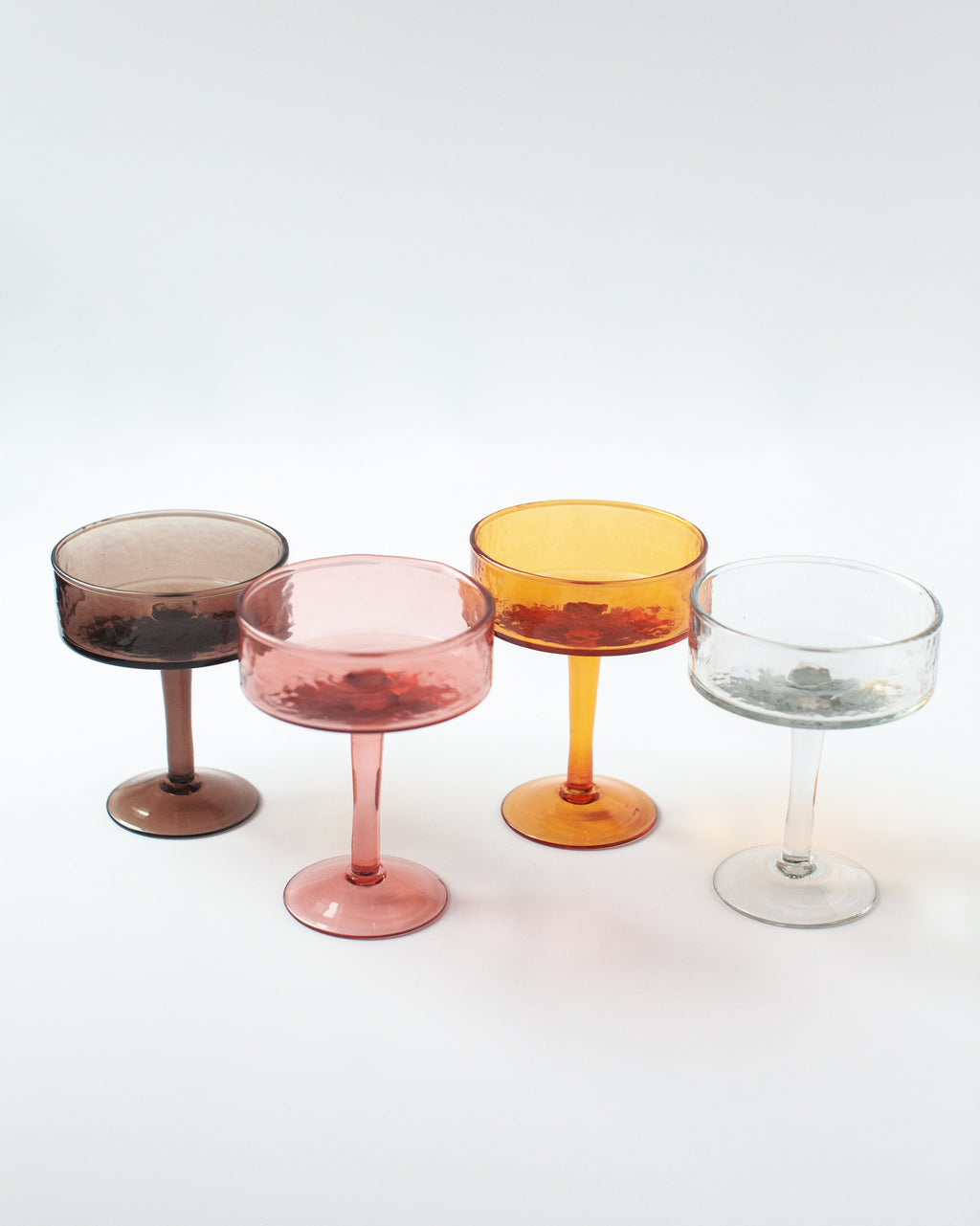 Handblown hammered coupe cocktail glasses pair in colored recycled glass on a table — view 2
