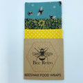 Reusable blue bee floral beeswax food wrap covering a sandwich and ceramic bowl