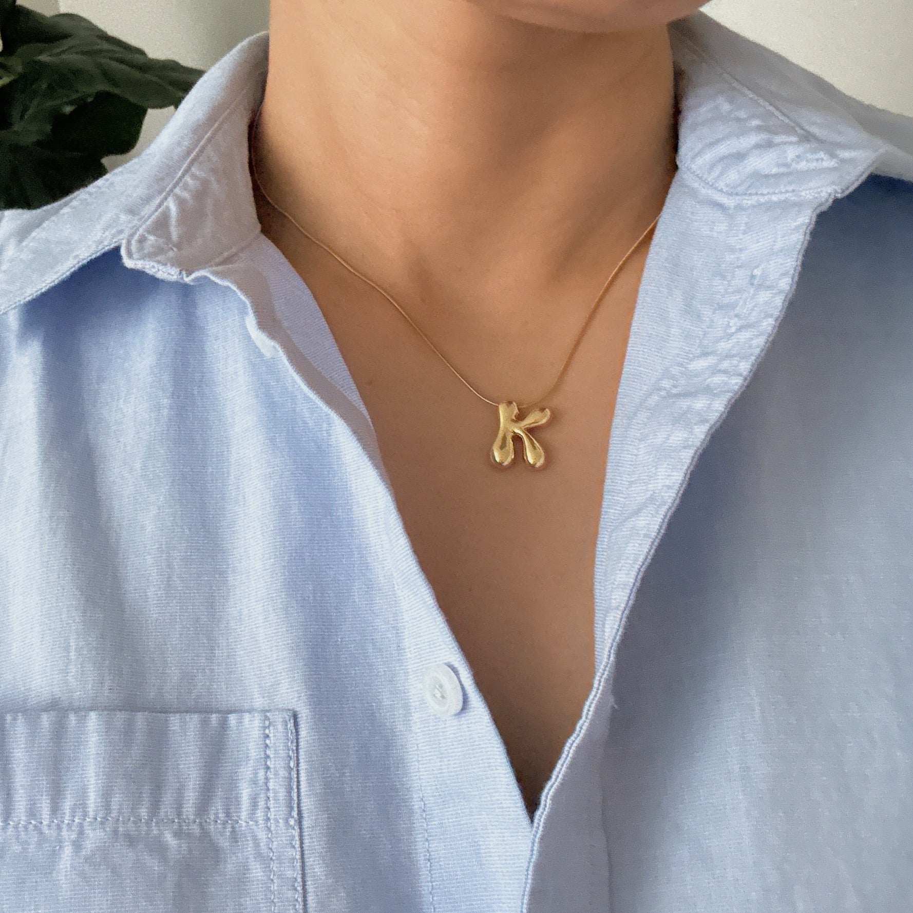 Gold plated balloon letter initial necklace with a stainless steel chain on a plain background — view 3