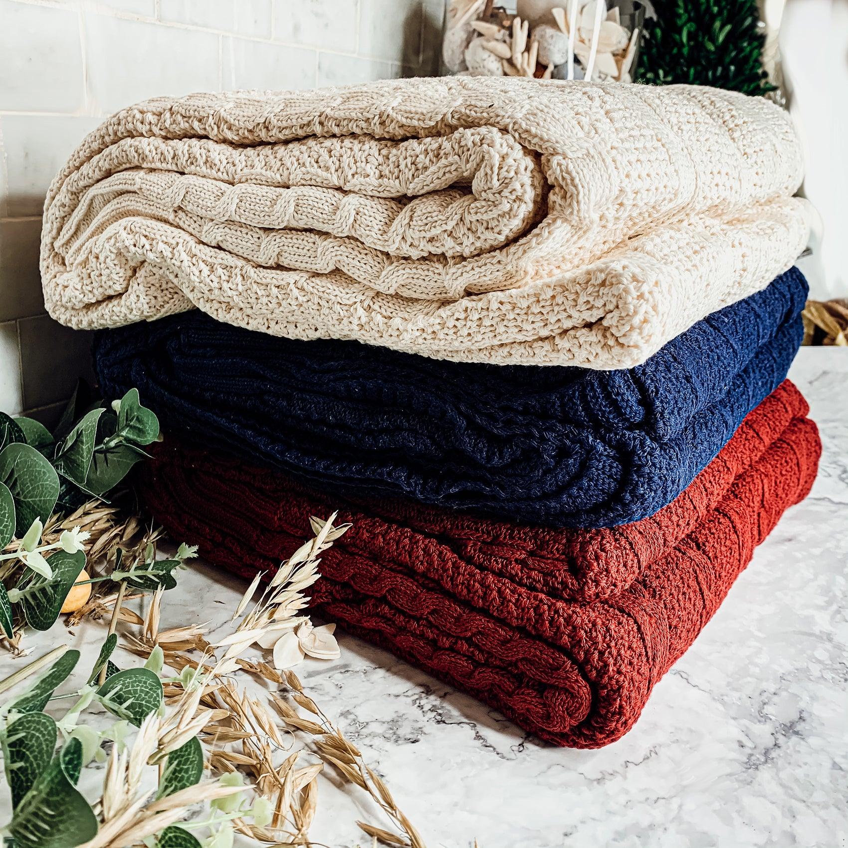 Ivory cable knit sweater throw blanket made of a soft cotton blend, draped elegantly. — view 2