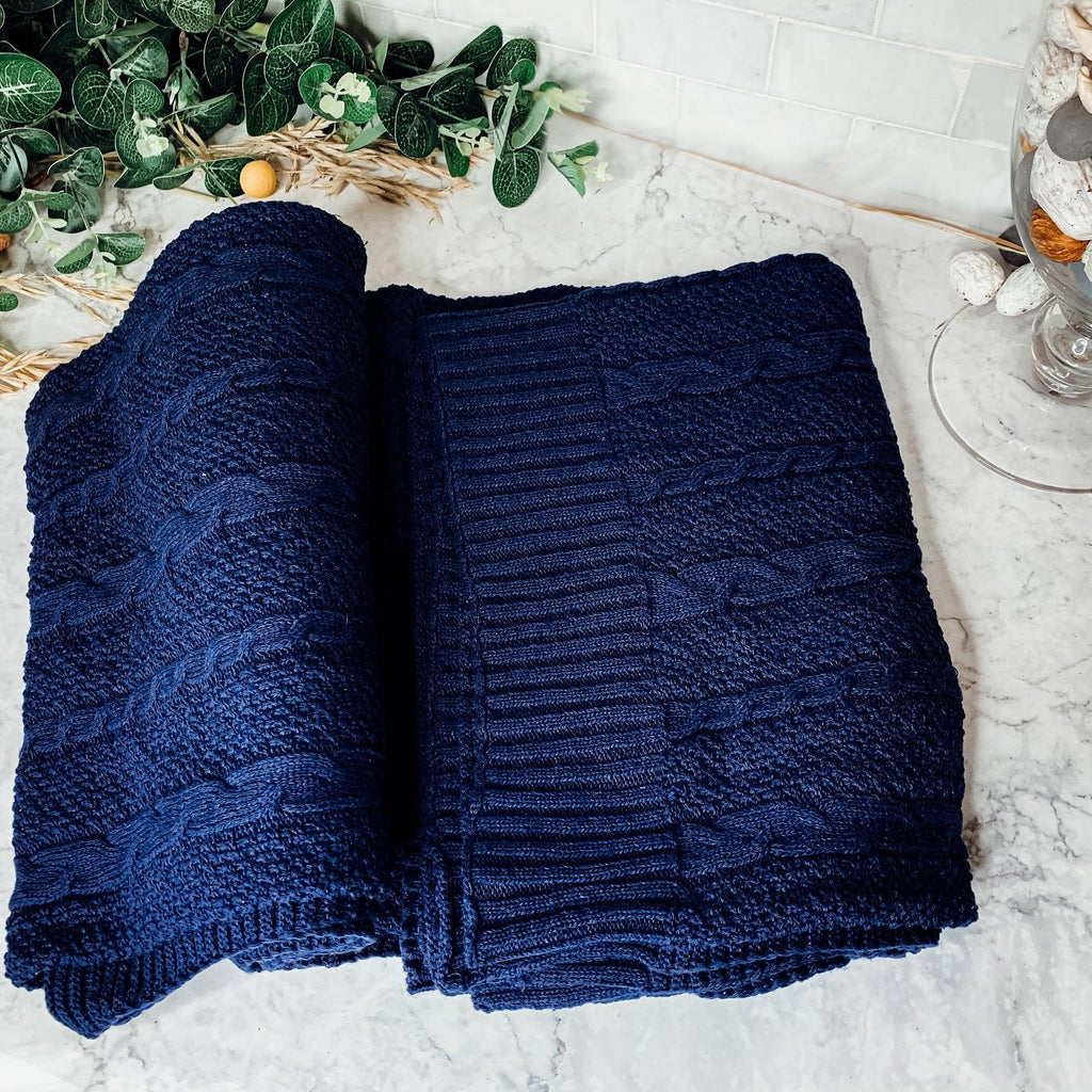 Ivory cable knit sweater throw blanket made of a soft cotton blend, draped elegantly. — view 5