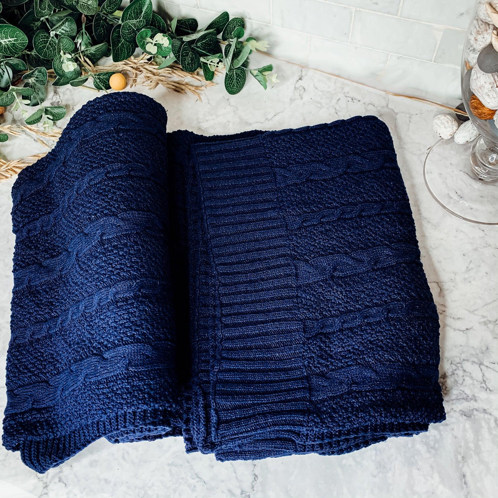 Ivory cable knit sweater throw blanket made of a soft cotton blend, draped elegantly. — view 5