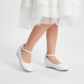 Girls faux leather wedge shoes with a big bow detail, perfect for elegant formal occasions.