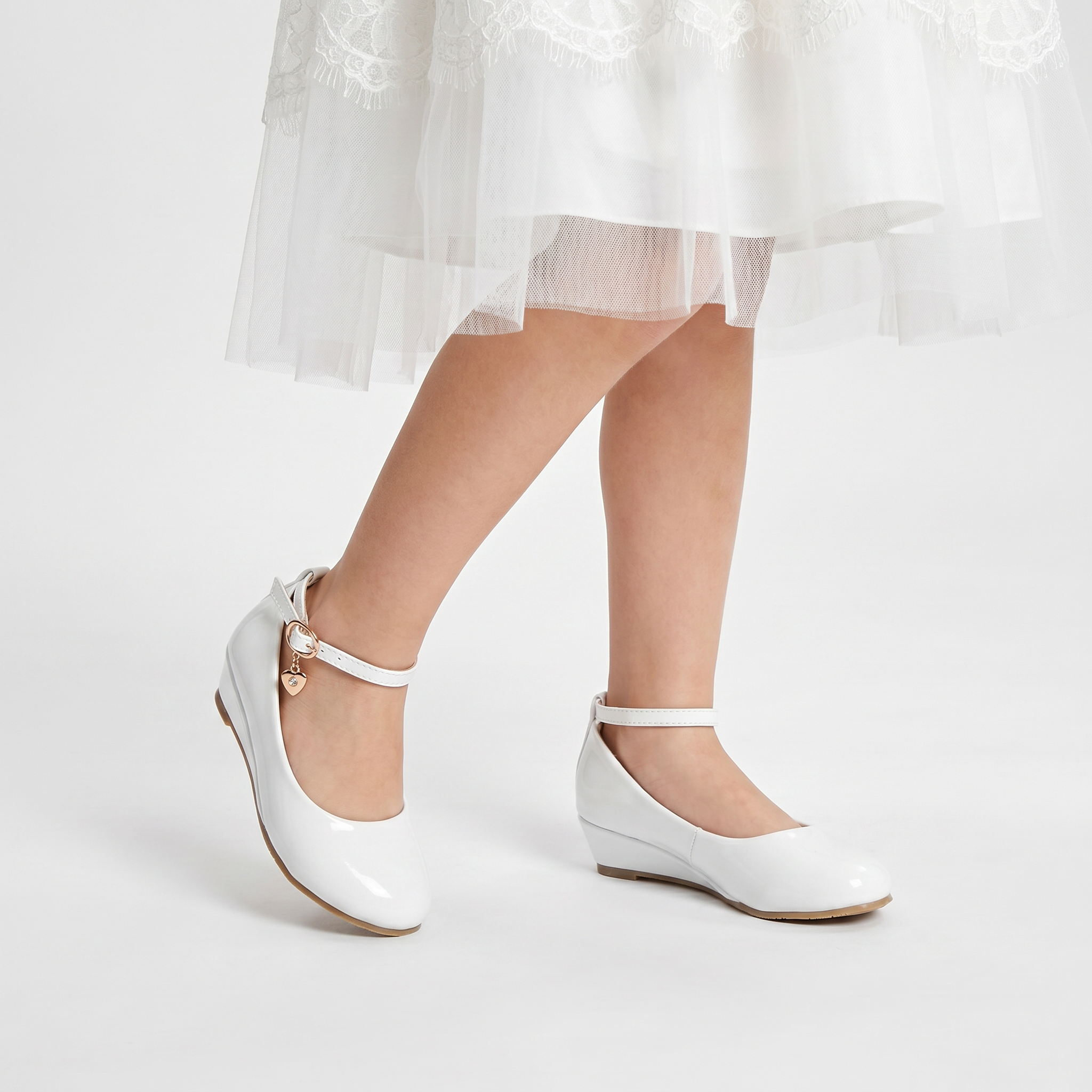Girls faux leather wedge shoes with a big bow detail, perfect for elegant formal occasions.