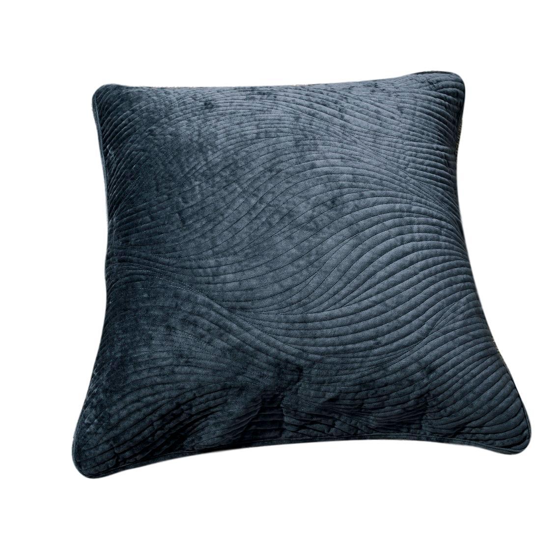 Navy blue velvet cushion cover with wavy matelassé stitching shown styled on a bedroom bed.