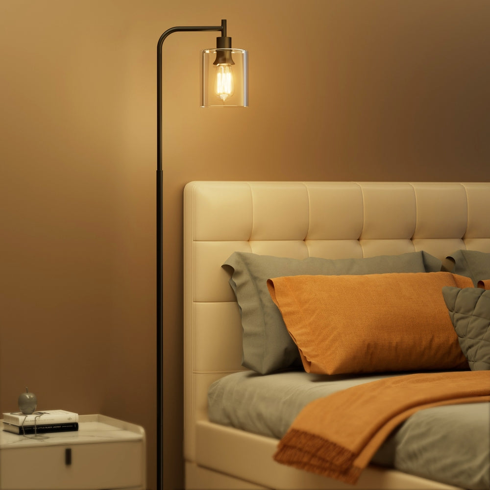 Modern black metal floor lamp with glass shade illuminating a stylish living room setting — view 4
