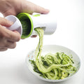 Heavy duty stainless steel vegetable spiralizer slicing a fresh green zucchini into curly vegetable pasta noodles
