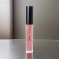 Tropical coral pink lip gloss tube with doe foot applicator and luminous sheer shimmer.