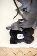 Natural sheepskin dog toy bone in black, filled with eco-friendly wool offcuts and hidden bell