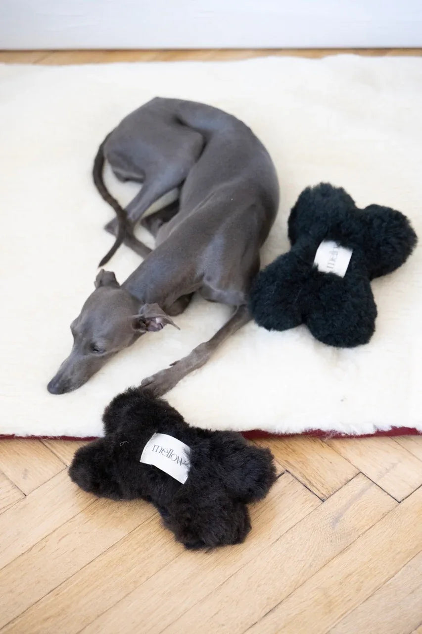 Natural sheepskin dog toy bone in black, filled with eco-friendly wool offcuts and hidden bell — view 2