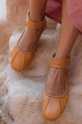 Tan genuine leather ballet flats with ankle strap cuff and back zipper on a white background