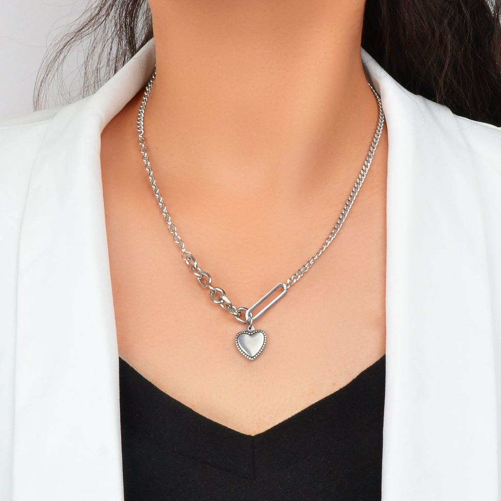 Layered multiple silver chain necklace featuring a polished love heart charm pendant on a display