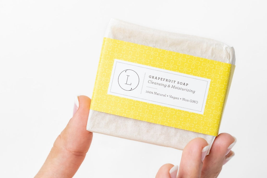 Two natural pink grapefruit handmade soap bars packed in a rustic cotton drawstring bag
