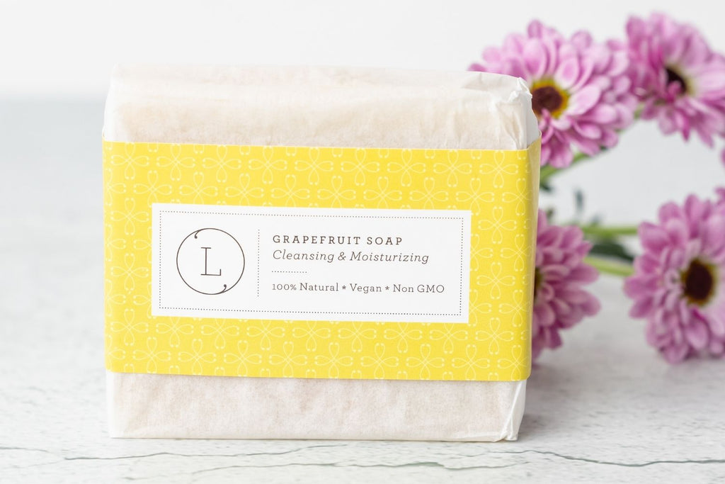 Two natural cold process essential oil soap bars resting inside a reusable cotton drawstring bag — view 2