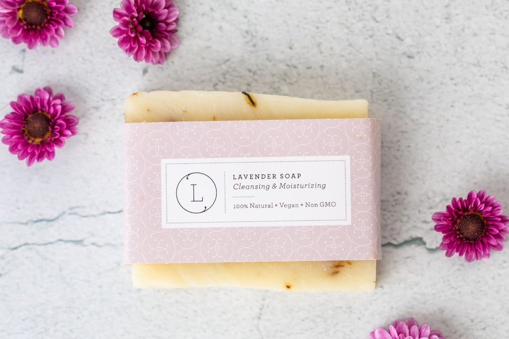 Two natural cold process essential oil soap bars resting inside a reusable cotton drawstring bag — view 4