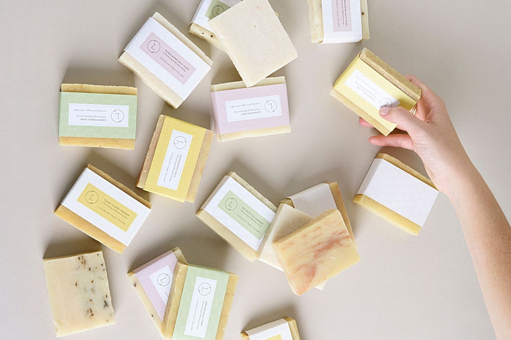 Two natural cold process essential oil soap bars resting inside a reusable cotton drawstring bag