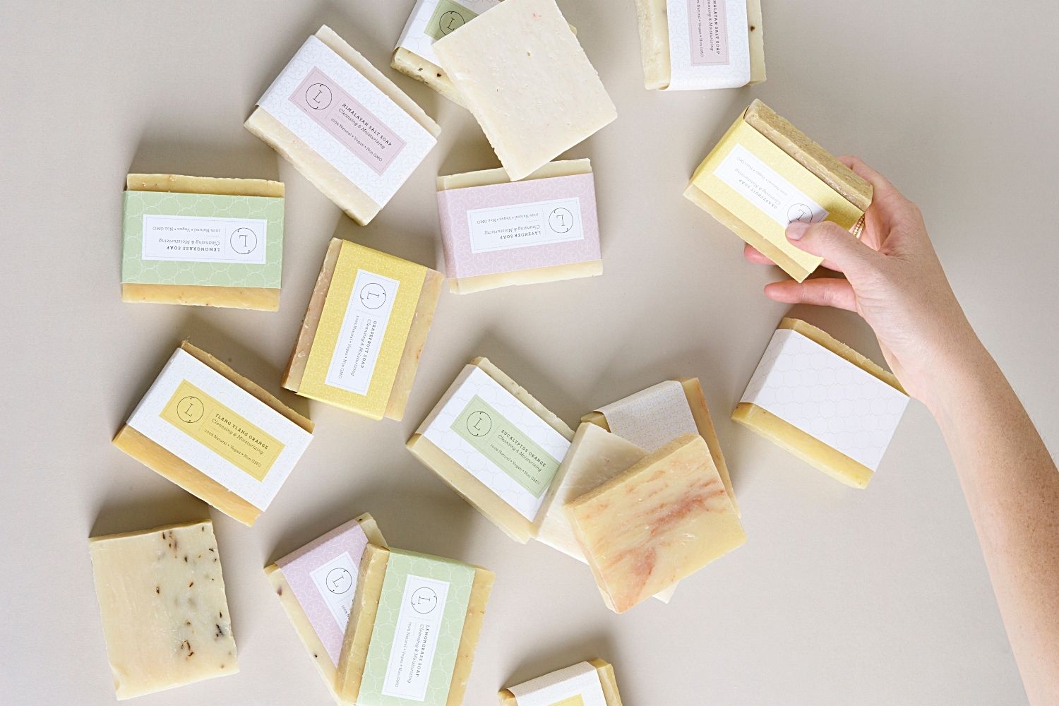 Two natural cold process essential oil soap bars resting inside a reusable cotton drawstring bag