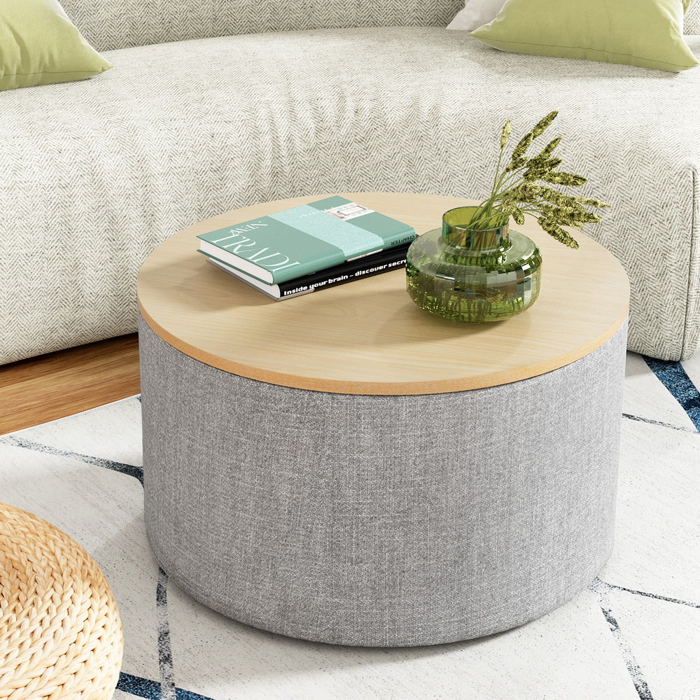 Round grey faux linen storage ottoman with a removable wood lid and concealed blanket compartment.