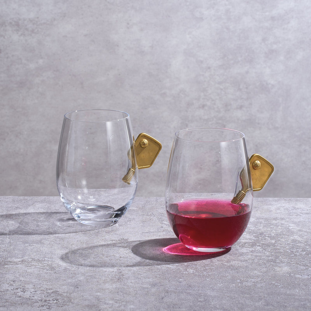 Two pickleball stemless wine glasses with decorative 3D gold racket details on a plain background — view 2