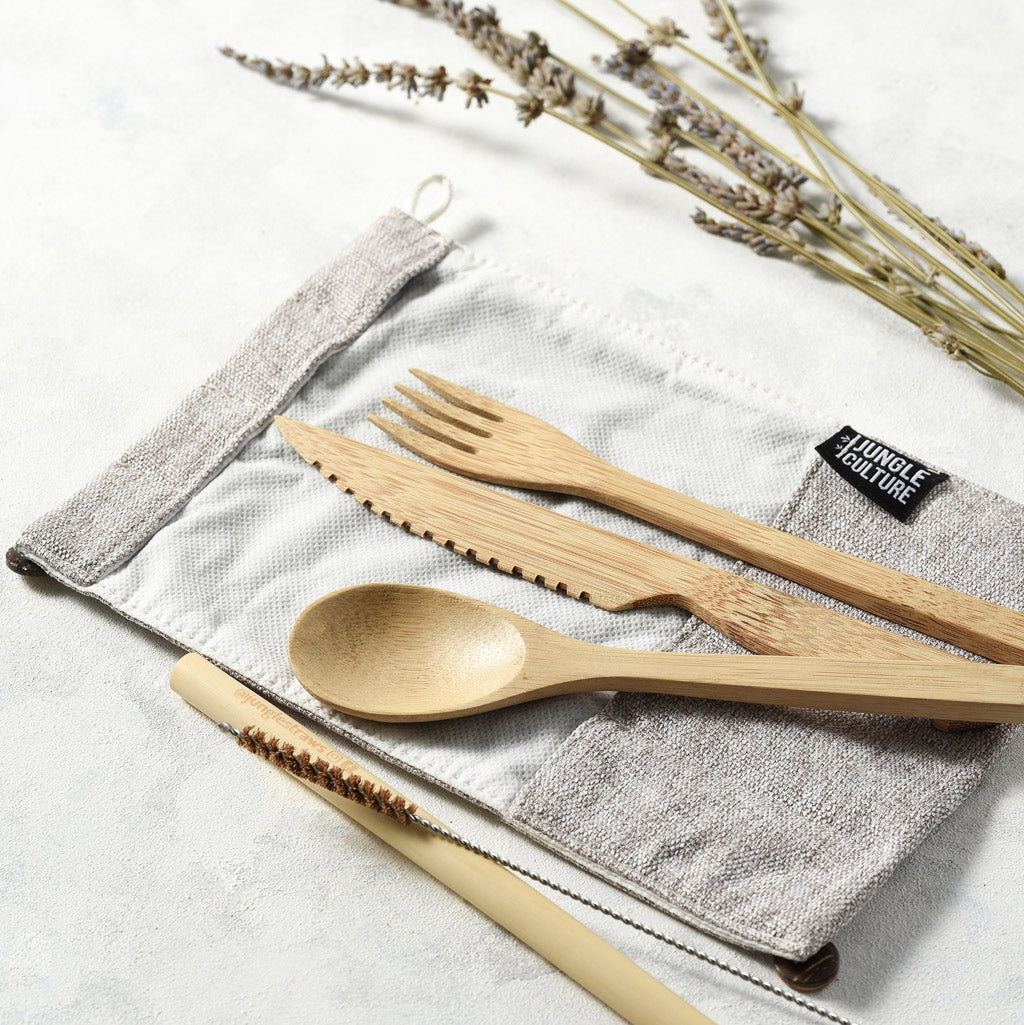 Organic bamboo travel cutlery set with light grey jute pouch, fork, knife, spoon, and straw