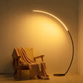 Modern RGBW curved floor lamp in black metal emitting colorful ambient lighting in a room