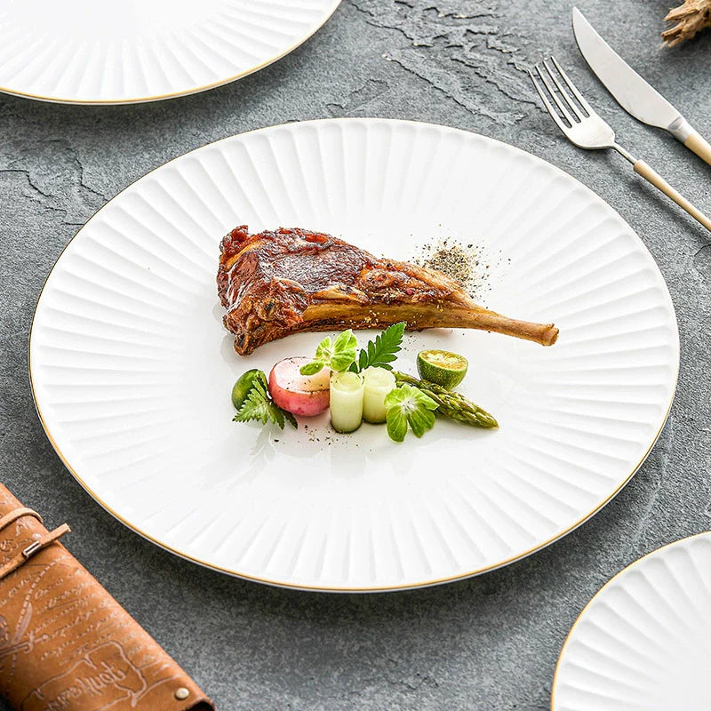 White ceramic dinner plate with pleated texture and a hand-painted gold rim
