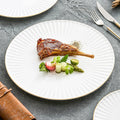 White ceramic dinner plate with pleated texture and a hand-painted gold rim