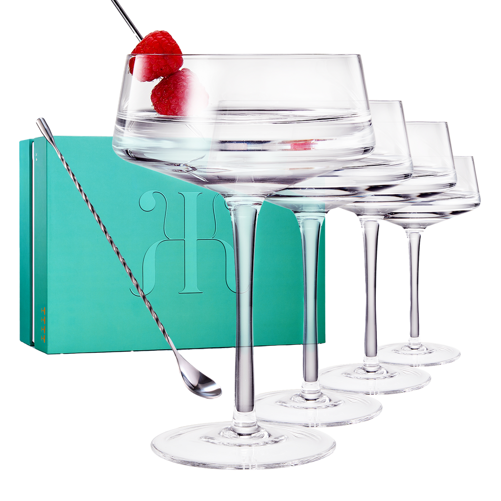Four luxury glass martini coupes with an elegant silver mixing spoon for cocktail entertaining