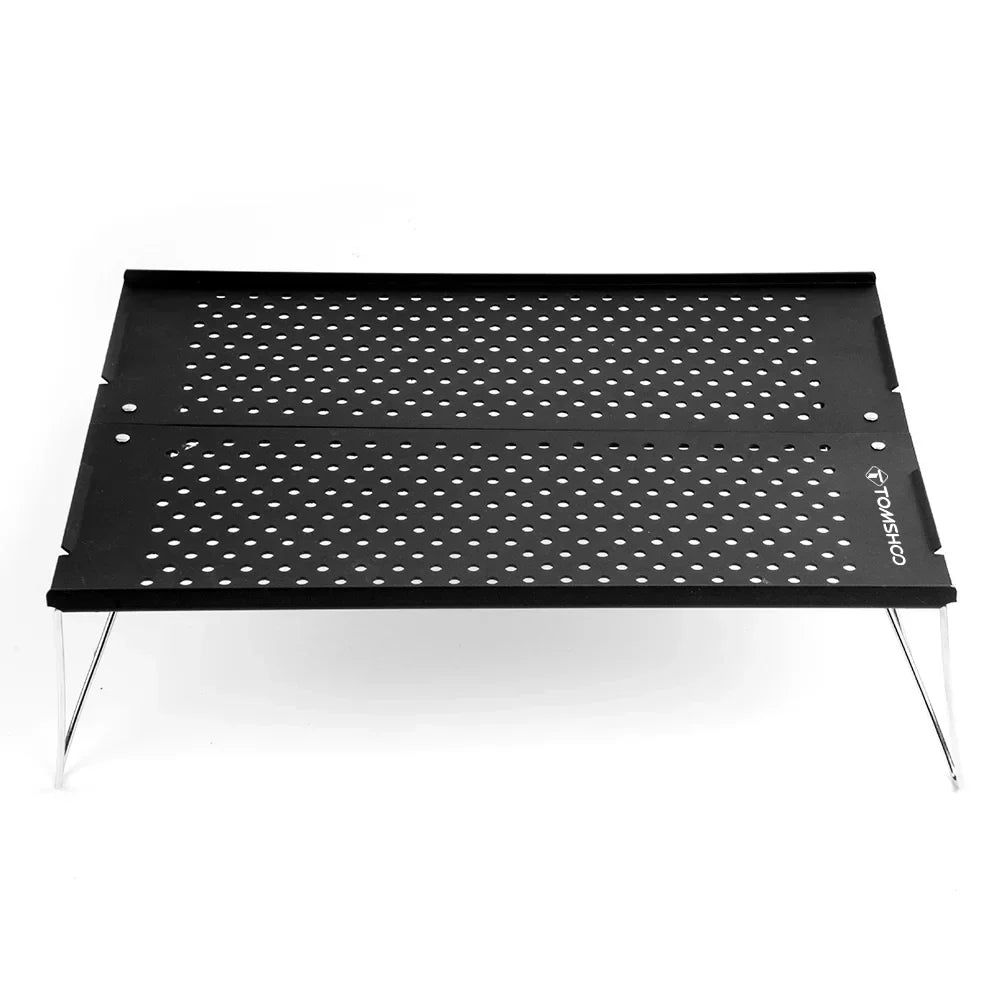Compact metal folding camping table set up outdoors on green grass for a picnic