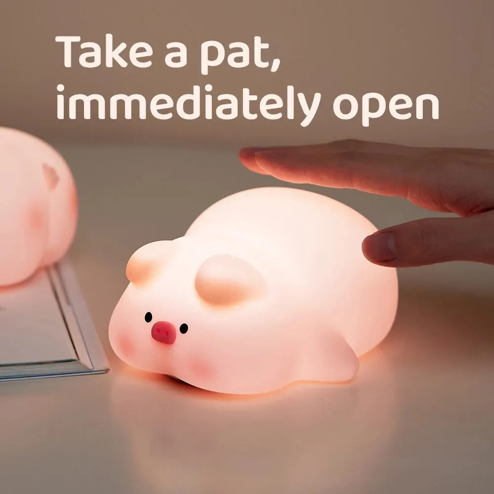 Cute pig night light made of soft white silicone emitting a warm glow on a desk — view 4