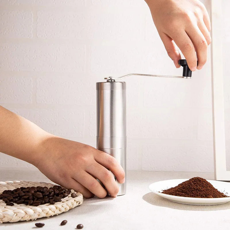 Silver stainless steel manual coffee grinder with hand crank and ceramic burr mechanism — view 3