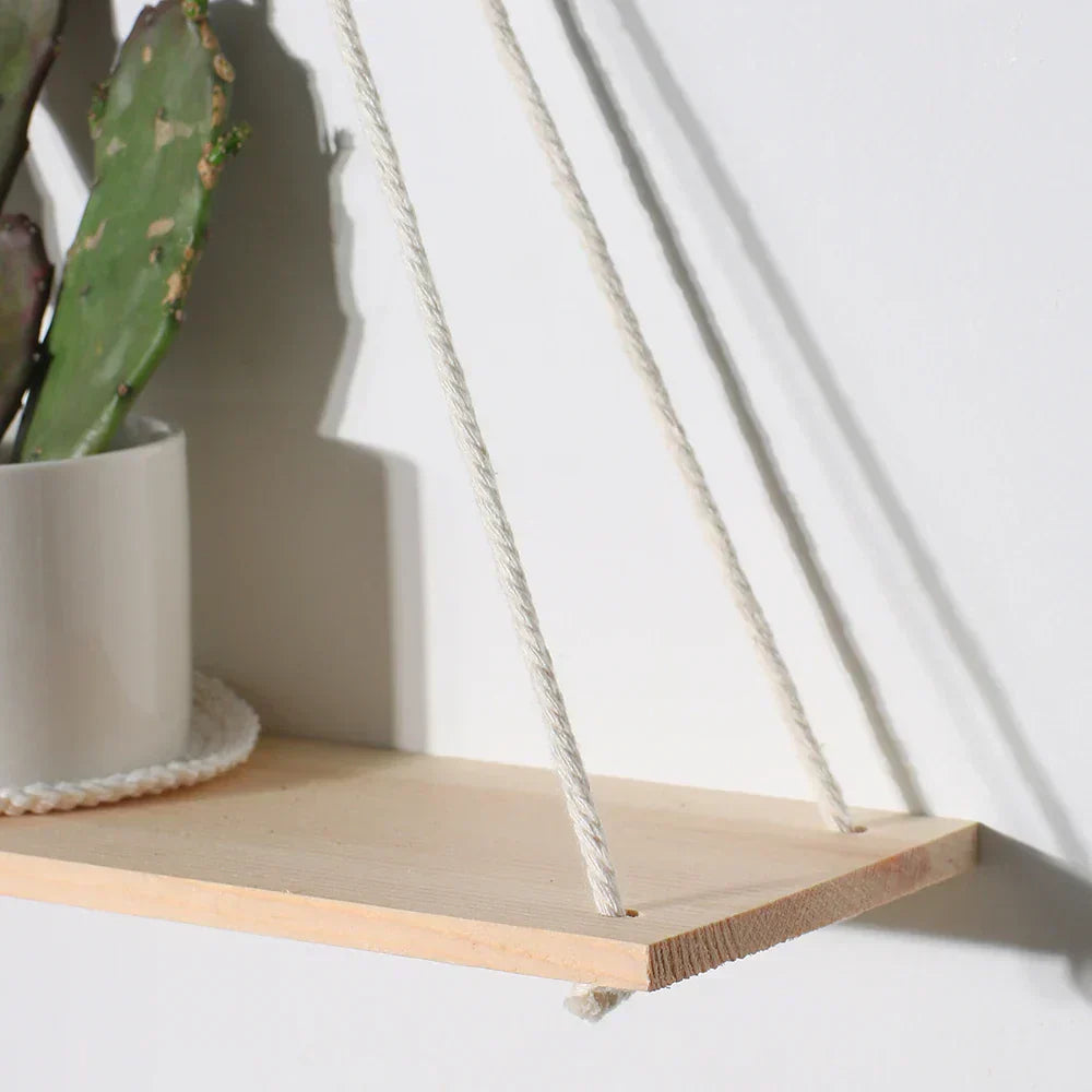Handmade boho macrame wood wall shelf displaying small plants and home decor items against a wall — view 2