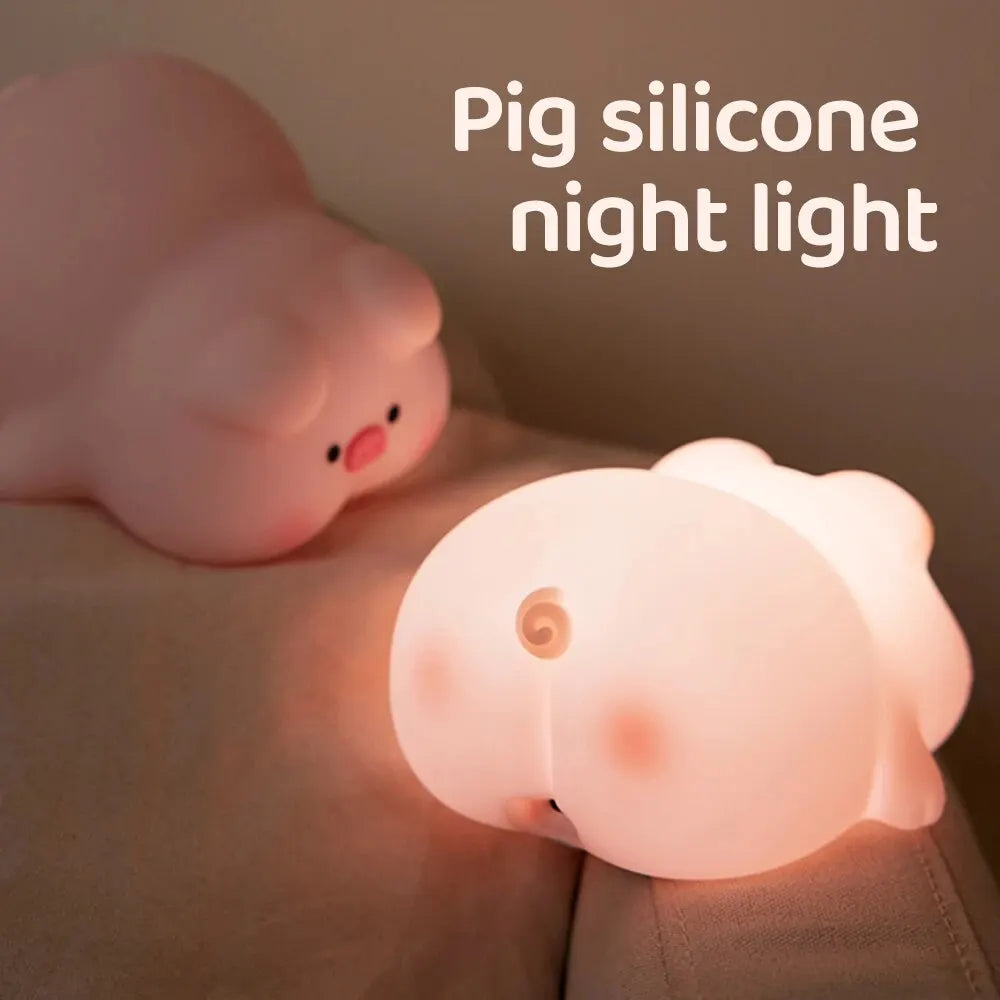 Cute pig night light made of soft white silicone emitting a warm glow on a desk — view 3