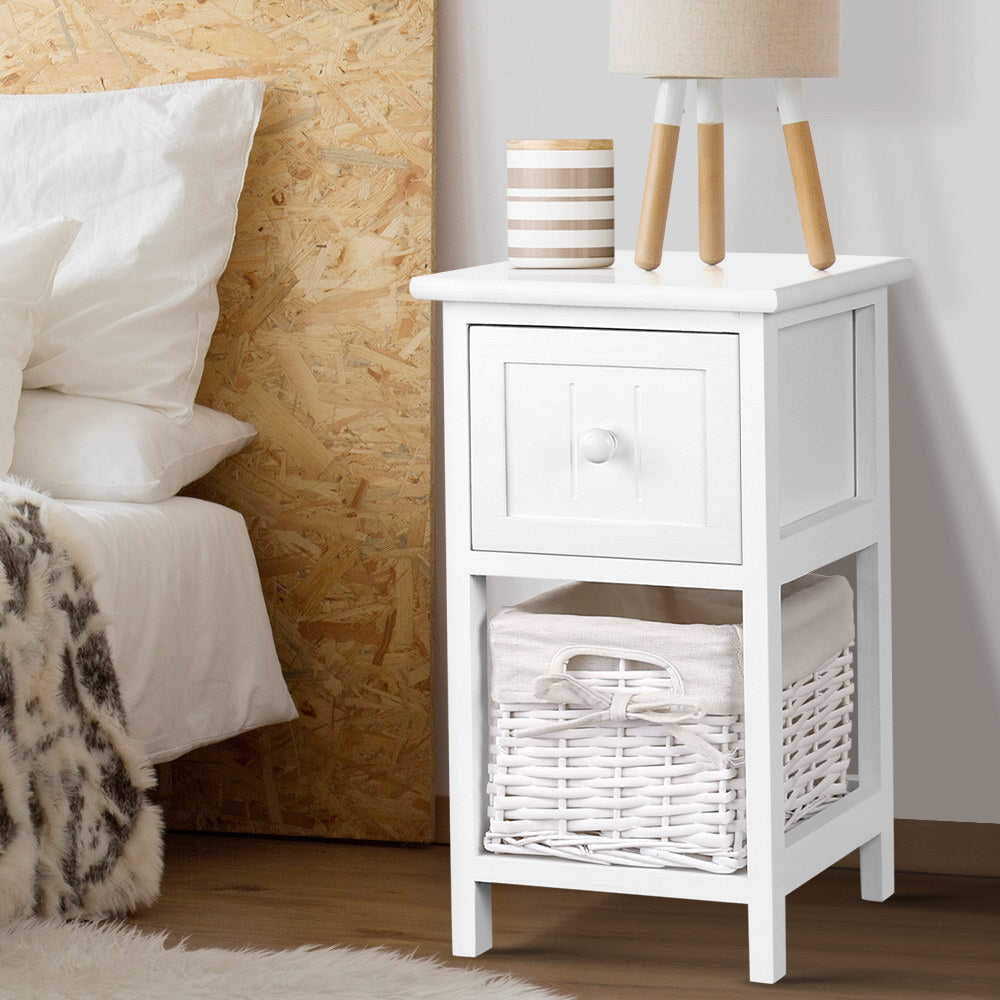 Two rustic white wood bedside tables with smooth top drawers and wicker storage baskets.