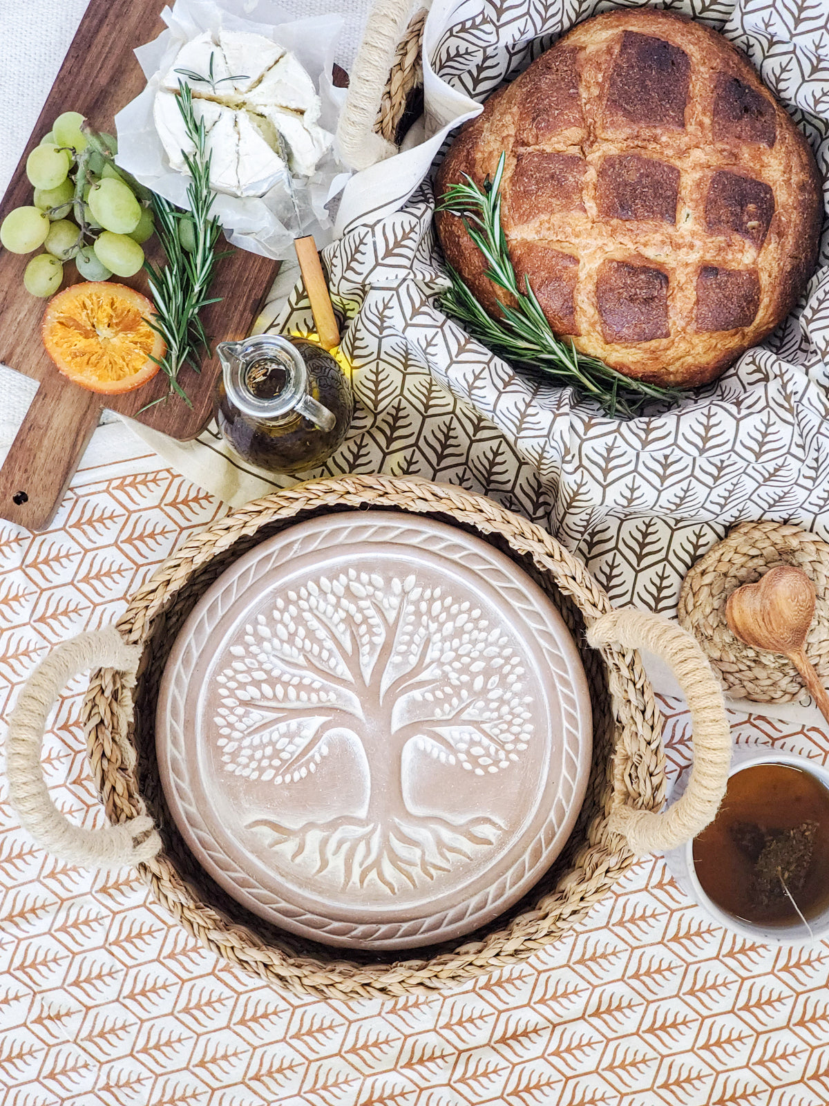 Terracotta tree of life bread warmer stone with woven seagrass basket and printed cotton tea towel — view 2